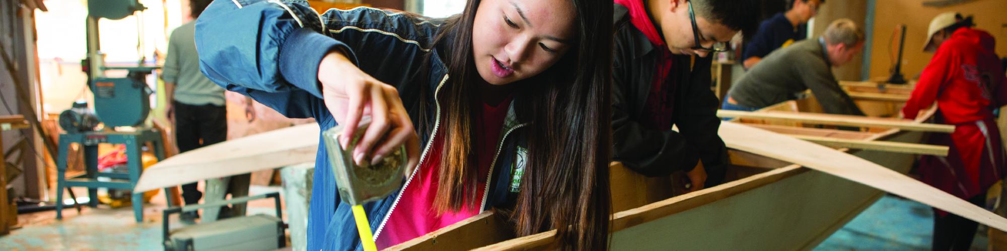 Students cooperate to build a boat in woodworking class