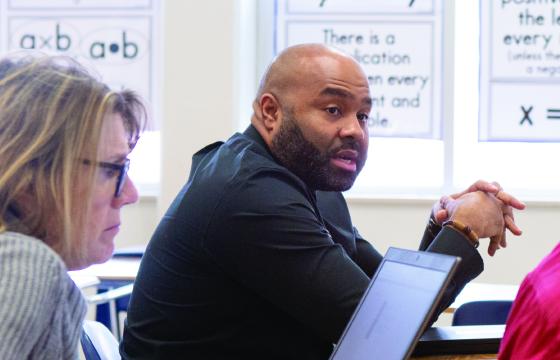 Four teachers meet in a classroom with a young male student.
