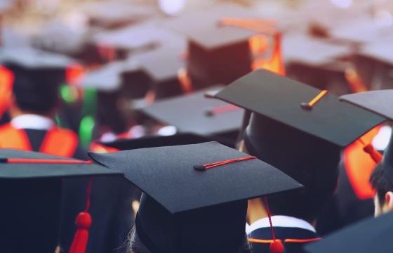 Student in graduation caps attend a commencement ceremony.