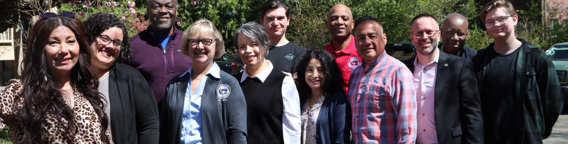 Board members standing in front of flowering trees.